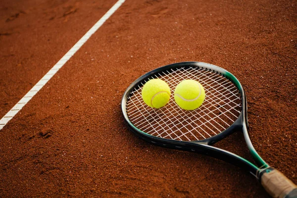 Tennis racket with balls on clay