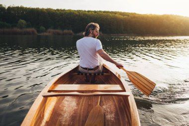 Yakışıklı sakallı adam nehirde yelken açıyor.