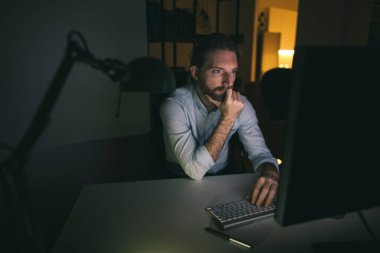 Adam uzun saatler çalışıyor. Bilgisayarda çalışan sakallı adam.