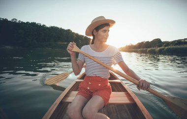 Günbatımında kanoyla gezen genç bir çift. 