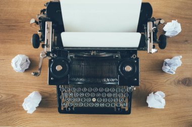 Kırsal ahşap arka planda, etrafı buruşmuş kağıtlarla dolu bir daktilo. İlham sorunu kavramı