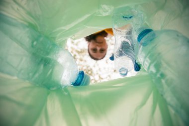 Kadın plastik çöp topluyor. Paketten görüntüle