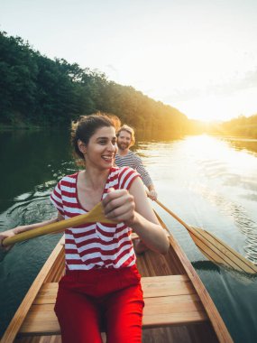 Gün batımında sakin bir nehirde kano yapan sevimli bir çift.