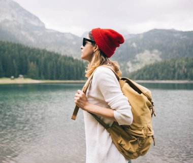 Dağların ve gölün arkasında sırt çantalı bir kız turist.