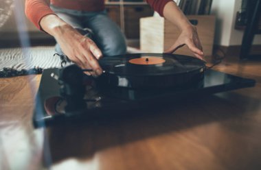 Vinil plak çalıyorum. Kadının yerde oturup pikapta müzik çalarkenki görüntüsü.