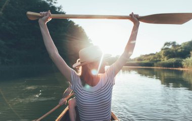 Yakışıklı adam ve kadın nehir batımında kanoyla geziyorlar. 