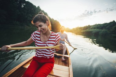 Gün batımında sakin bir nehirde kano yapan sevimli bir çift.
