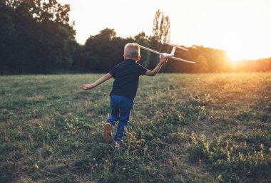 Planör uçak modeliyle oynayan çocuğun arka görüntüsü