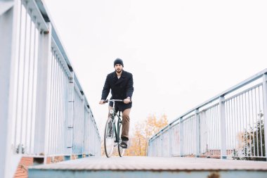 Bisikletli hippi eğleniyor. Sakallı adam parkta bisiklet sürmeyi sever.