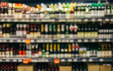 Süpermarkette raftaki içki şişelerinin bulanık görüntüsü. Süpermarkette şarap şişeleriyle çözünmüş raf.