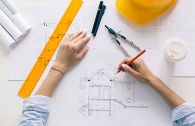 Kadın mimar bir plan çizer, tasarım, geometrik şekiller ofis masasındaki büyük kağıt üzerine kurşun kalemle çizer..