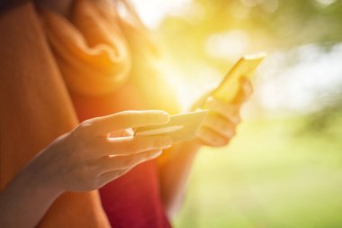 Kredi kartı ve akıllı telefon kullanan genç bir kadının orta kesimi.