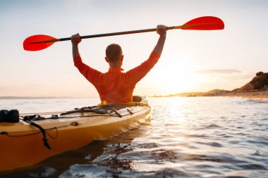 Aktif tatillerin tadını çıkar. Aktif kıdemli adamın arka görünüşü kano küreklerini yüksek tutuyor