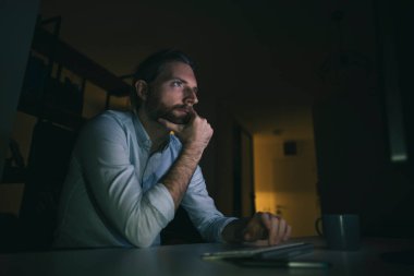 Bilgisayarda geç saatlere kadar çalışan sakallı adam. Adam evinden saatlerce çalışıyor.