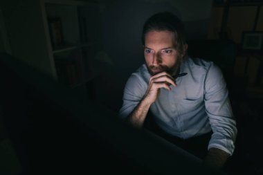 Bilgisayarda geç saatlere kadar çalışan sakallı adam. Adam evinden saatlerce çalışıyor.