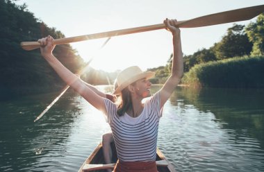 Yakışıklı adam ve kadın nehir batımında kanoyla geziyorlar. 