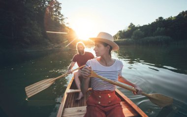 Yakışıklı adam ve kadın nehir batımında kanoyla geziyorlar. 