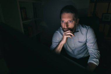 Bilgisayarda geç saatlere kadar çalışan sakallı adam. Adam evinden saatlerce çalışıyor.