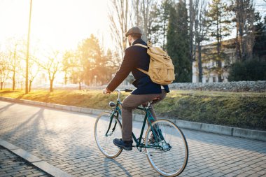 Bisikletli hippi eğleniyor. Sakallı adam parkta bisiklet sürmeyi sever.