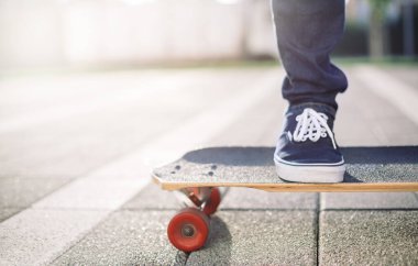 Kaykay yapmak. Kaykaycı bacaklarını uzun kaykayla kapat