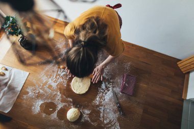 Mutfak masasında ekmek hamuru yoğuran kadının yüksek açılı görüntüsü. Ev yapımı hamur işi.