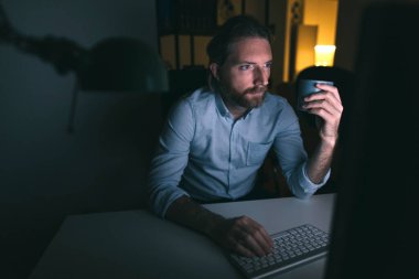 Adam uzun saatler çalışıyor. Bilgisayarda çalışan sakallı adam.