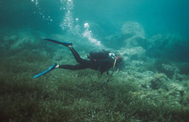 Kayalık zemini olan bir adam suyun altına dalıyor.
