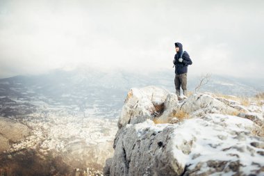 Kayalıklarda erkek turist kışın arka planda