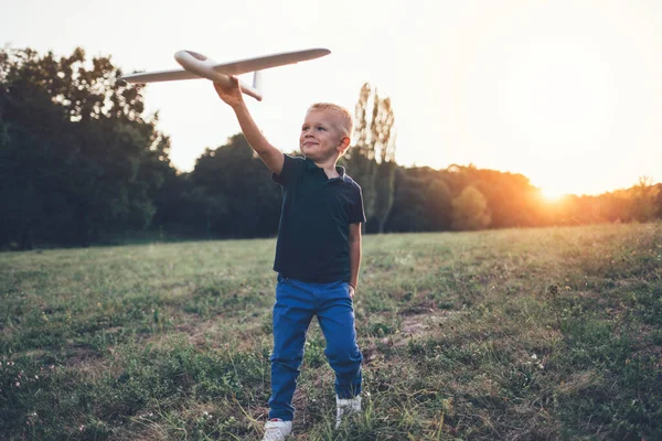 Smiling child playing with airplane model. Boy dream about flying a plane