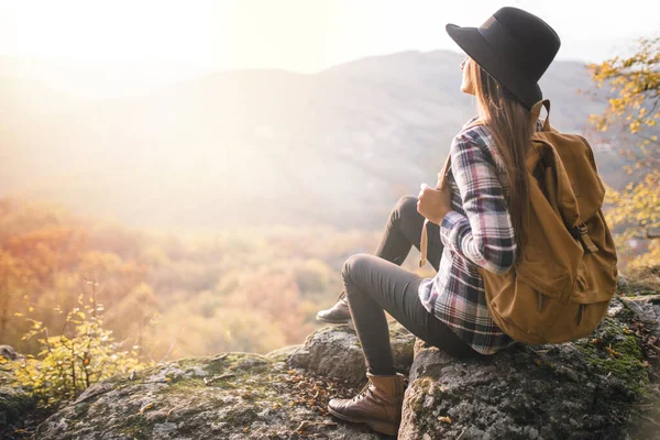 Uçurumda oturan şapkalı bir kız.