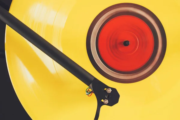 Close up of turntable tonearm play yellow color vinyl record