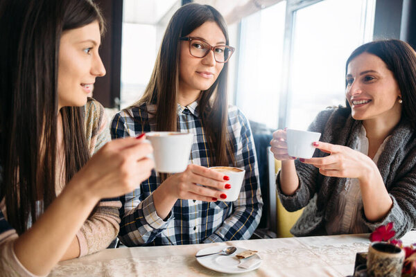 Attractive girls sitting in the cafe and drinking coffee