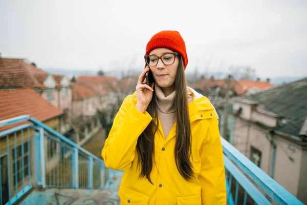 Wanita Muda Berjas Hujan Kuning Menggunakan Ponsel Pintar — Stok Foto