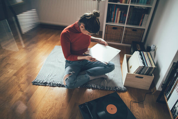 Audiophile girl listening vinyl records at her home. Hipster girl enjoy her vinyl records collection