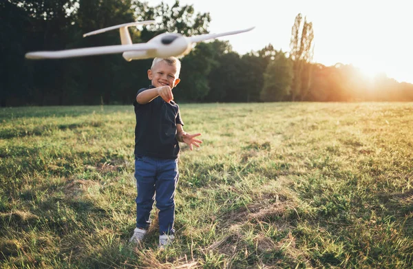 Boy enjoy playing with airplane model. Smiling boy throwing airplane, dreaming about flying