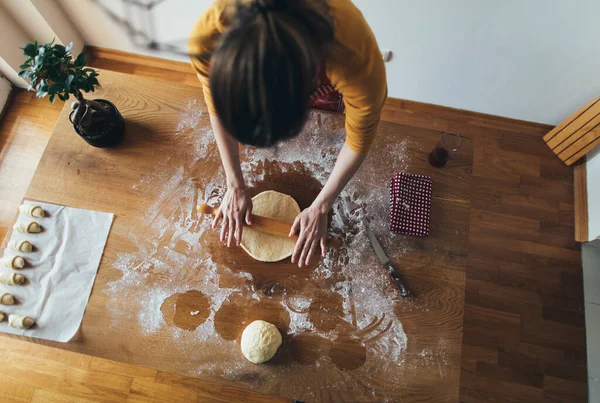 Mutfak masasında ekmek hamuru yoğuran kadının yüksek açılı görüntüsü. Ev yapımı hamur işi.