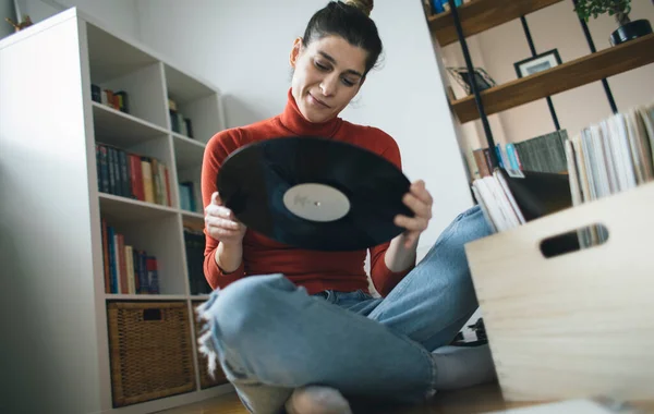 Hippi kızın elinde en sevdiği plak plağı var. Düşük açılı bir kız evde müzik dinlemekten hoşlanıyor.