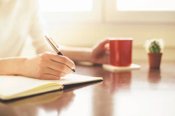 Bir kadının kahve fincanı tutarken ve yazarken