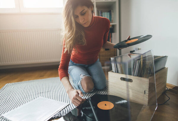 Молодая аудиофилка играет виниловую пластинку на проигрывателе у себя дома. Наслаждайтесь виниловыми пластинками
