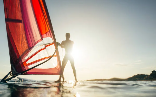 Ung Mand Opløfte Sejl Til Windsurfing Solnedgang Havet Silhuet Windsurfer - Stock-foto