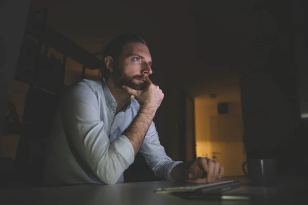 Bilgisayarda geç saatlere kadar çalışan sakallı adam. Adam evinden saatlerce çalışıyor.