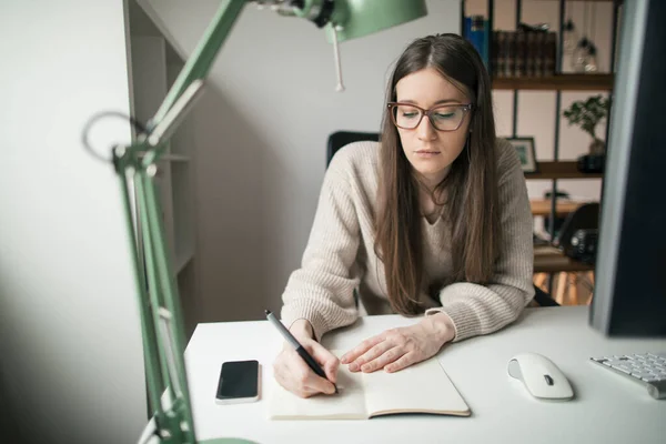 Masaüstü bilgisayarı üzerinde çalışan odaklanmış genç bir kadın. Ofisinde bilgisayarla çalışan genç bir iş kadını.