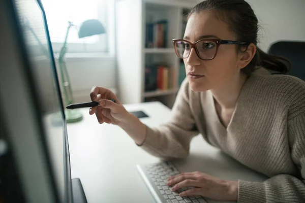 Young woman programming at her home office. Young female programmer reading computer codes on desktop PC