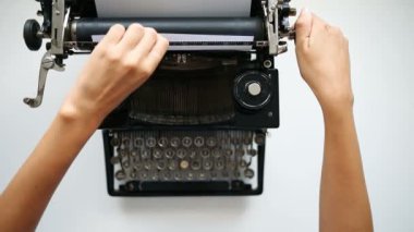 Kadın ellerinin yüksek açılı görünümü daktiloya kağıt sokuyor