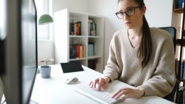 Masaüstü bilgisayarında çalışan genç bir iş kadını. Genç bayan uzun saatler çalışıyor.