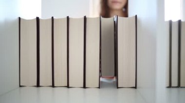 Kütüphanede kitap seçen bir kız öğrenci.