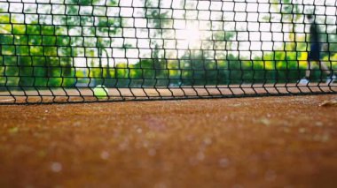 Arka planda erkek bahçıvanın olduğu bir tenis ağı. Tenis kortu bakımı