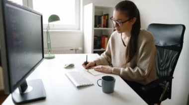 Masaüstü bilgisayarı üzerinde çalışan odaklanmış genç bir kadın. Ofisinde bilgisayarla çalışan genç bir iş kadını.