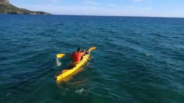 Kanocu adam kanoya arkadan bakıyor. Deniz kanosu, kano, kürek.