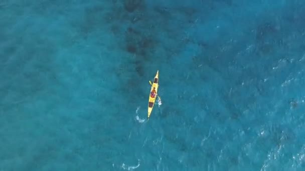 カヤックを漕ぐカヤックマン ターコイズブルーの海に黄色のカヤックの高角度追跡 シーカヤック — ストック動画